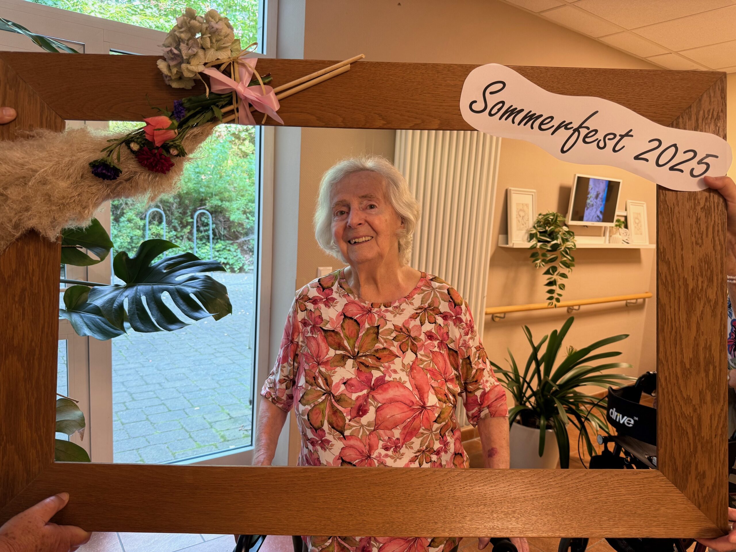 eine Bewohnerin hinter einem geschmückten Sommerfest-Bilderrahmen